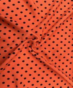Crêpe polyester fond orange pois noirs